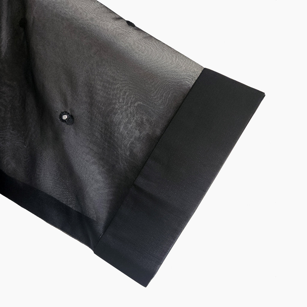 Close-up of hand mirror embellishments on a sheer mesh women's top